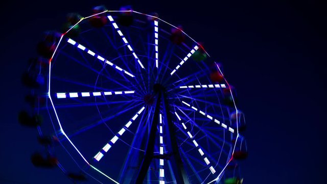 The night comes on the background of a Ferris wheel