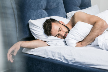 close-up view of handsome young bearded man sleeping in bed at home