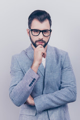 Successful young brutal bearded brunet banker in formal wear and black trendy glasses is standing isolated on a pure background and looks at the camera