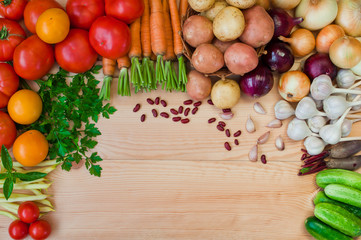 Tomatoes, carrots, potatoes, onions and other vegetables on a wooden table