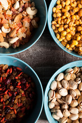 Mix of different type of nuts in blue bowls on wooden background