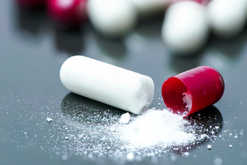 medical drug capsule and powder on black background