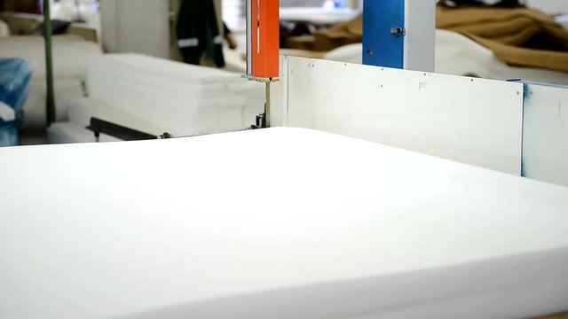 Production of mattress with using machine on the plant is shown closeup. White foam rubber