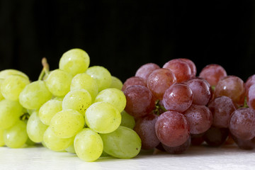 Fresh grapes on a white table and black background.