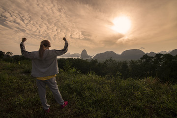 Happy girl with rise hand up on mountain,look at the sunrise beautiful view in morning.