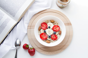 Strawberry Oatmeal. Healthy breakfast top view. Healthy vegan lifestyle. Styled stock photography. Breakfast bowl: cereal, almond milk, bananas, berries and nuts. White photo