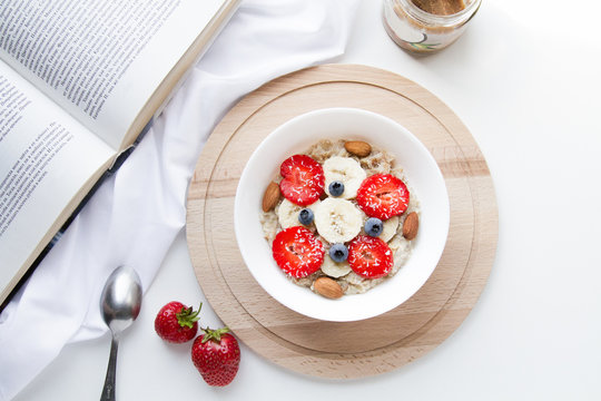 Strawberry Oatmeal. Healthy breakfast top view. Healthy vegan lifestyle. Styled stock photography. Breakfast bowl: cereal, almond milk, bananas, berries and nuts. White photo