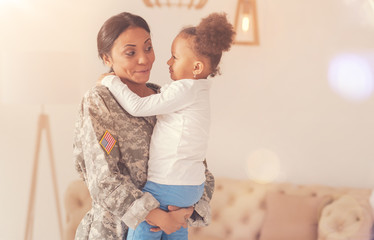 Joyful mother in camouflage holding her little daughter