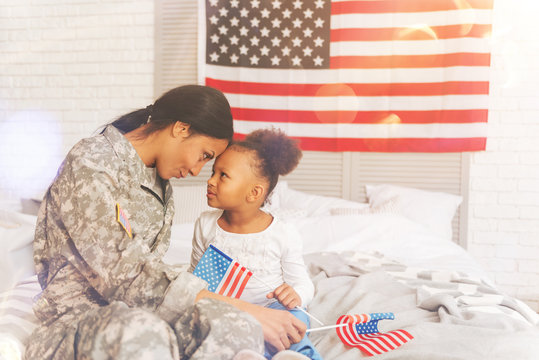 Military mother and daughter sitting forehead-to-forehead