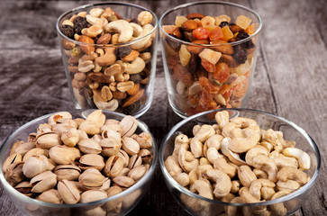 Healthy mix of dried nuts and sweets in was glass on wooden background in studio photo