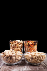 Healthy mix of dried nuts and sweets in was glass on wooden background in studio photo