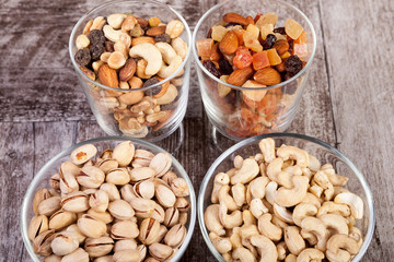 Healthy mix of dried nuts and sweets in was glass on wooden background in studio photo