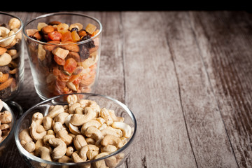 Healthy mix of dried nuts and sweets in was glass on wooden background in studio photo