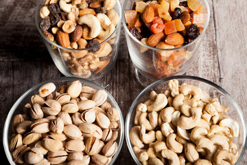 Healthy mix of dried nuts and sweets in was glass on wooden background in studio photo
