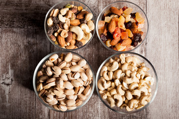 Healthy mix of dried nuts and sweets in was glass on wooden background in studio photo