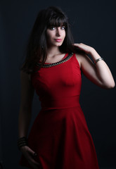 Belle femme brune portant une robe rouge posant sur un fond noir