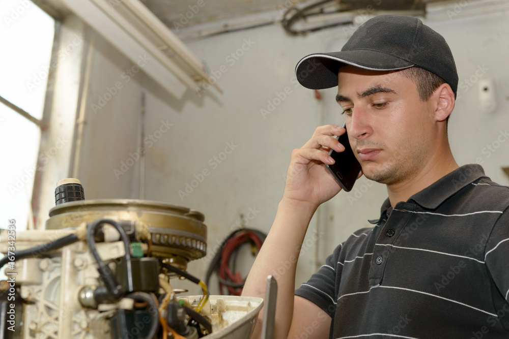 Sticker young man mechanic repairing motor boats and phone at customer