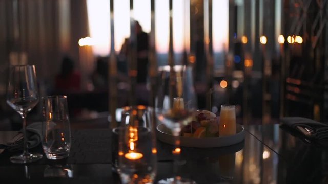 Modern restaurant, inside a skyscraper, view of glasse goblets at the bar counter, shallow depth of field. Interior lighting.
