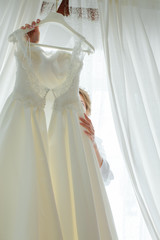 The bride is trying on a wedding dress, looking in front of her