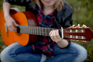  a girl sits on the grass with a guitar playing