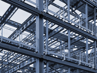 metal framework of new building development with a network of blue steel girders  and safety fencing
