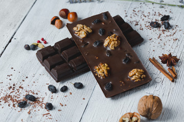 chocolate bar filled with different berries and nuts  lie old wooden table with cracked paint
