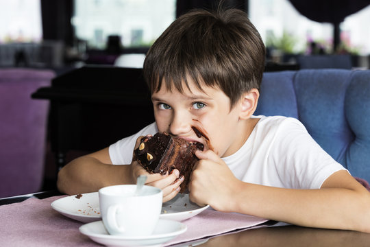 The boy is eating a large piece of cake in his hands 