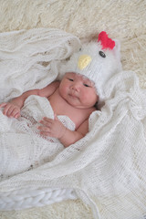 cute asian boy newborn portrait one month in chick hat lie down  on white background fur .
