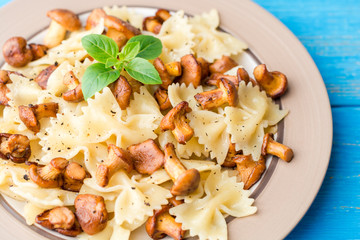 Farfalle pasta with chanterelles and basil on blue wooden table