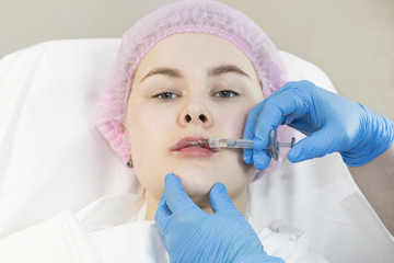 The process of cosmetic surgery of injection in the area of the lips of a woman