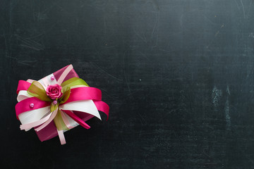 small handmade pink gift box with little rose and ribbons on dark background, flat lay, copy space for text. For the celebration of different holidays