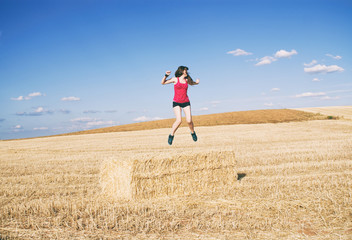 Mujer joven saltando en mitad de un campo en verano 