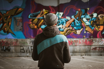 Graffiti artist standing near the wall - obrazy, fototapety, plakaty