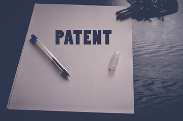 Patent written on white paper on wooden table, business concept