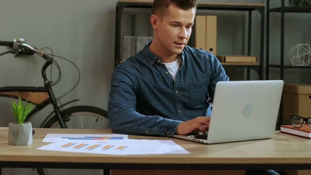 Attractive business man in casual shirt coming to the his office and start working in the laptop.