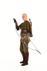 full length portrait of a blonde girl wearing green and brown medieval costume, holding a bow and...