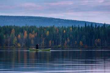 Autumn evening on the lake with fisherman in the boat, Lapland, Finland