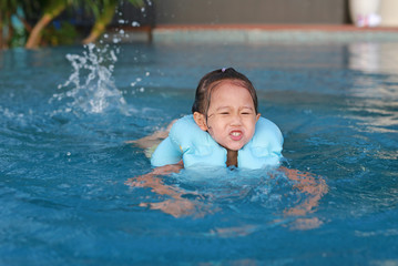 Fototapeta na wymiar Smiling cute girl playing in inflatable baby pool looking at camera.