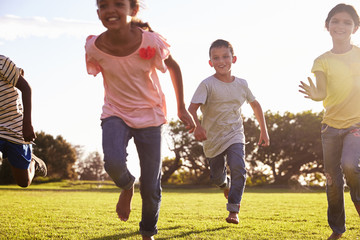 Obraz premium Three happy children running barefoot in a field in Summer