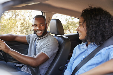 Young black couple in a car looking at each other smiling