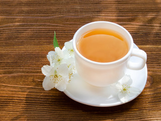 White mug of tea with jasmine on a wooden table. Close up, top view