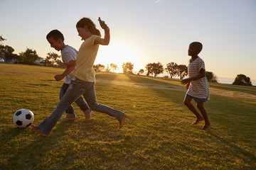 Three children playing football in a field
