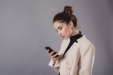 Portrait of a young attractive girl use smartphone isolated on a neutral gray background.