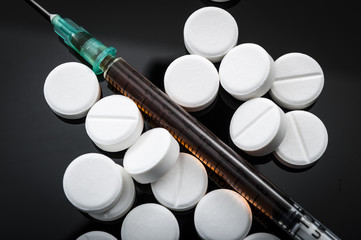 Opioid epidemic and drug abuse concept with closeup on a heroin syringe or other narcotics...