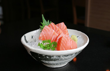 Salmon raw slice or salmon sashimi in Japanese style fresh serve on ice with fresh wasabi on black table.