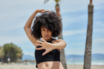 Pretty afro american woman training dancing on beach