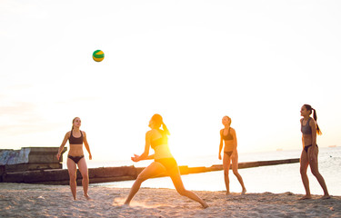 Group of young girls playing beach volleyball during sunset or sunrise