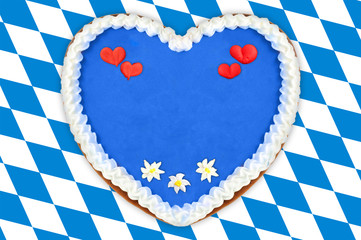 Obraz premium Oktoberfest Gingerbread heart with copy space on bavarian white blue flag.