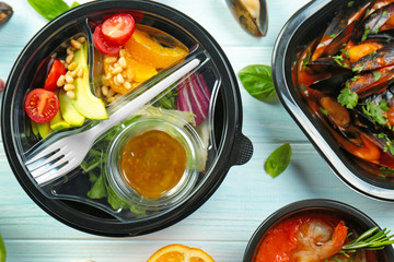 Plastic containers with delicious food on wooden table