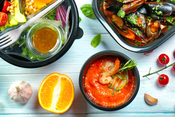 Plastic containers with delicious food on wooden table